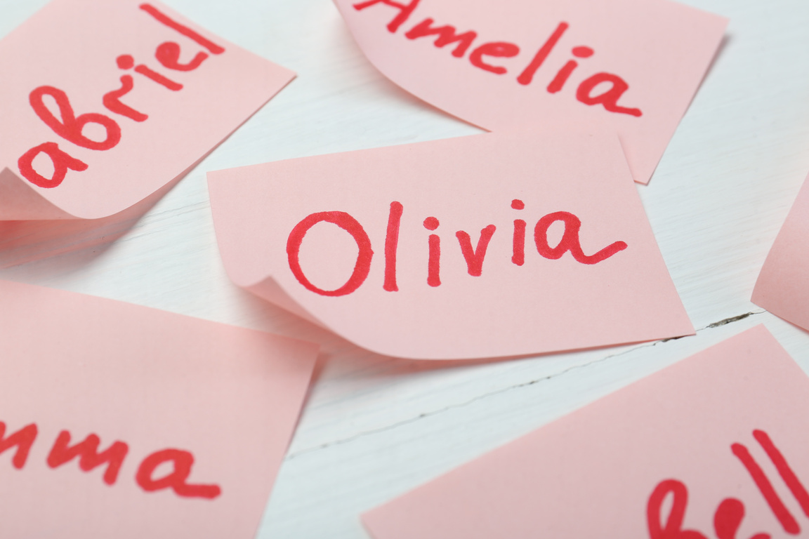 Paper Stickers with Different Names on White Wooden Table, Closeup. Choosing Baby's Name